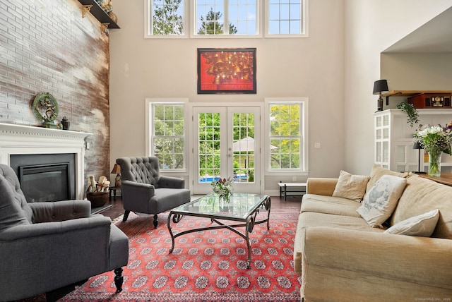 100 Pembroke Ter, Glastonbury, CT 06033 - living room featuring a high ceiling, wood finished floors, plenty of natural light, a glass covered fireplace, and french doors