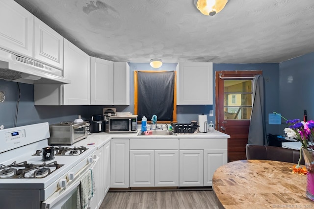 22 School St, New Britain, CT 06051 - kitchen with white gas range, a sink, stainless steel microwave, under cabinet range hood, and white cabinetry