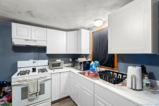 22 School St, New Britain, CT 06051 - kitchen with white gas range, under cabinet range hood, white cabinetry, and stainless steel microwave