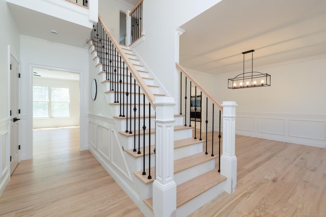 81 Nelson Dr, Burlington, CT 06013 - stairs featuring wood finished floors, a decorative wall, a chandelier, wainscoting, and ornamental molding