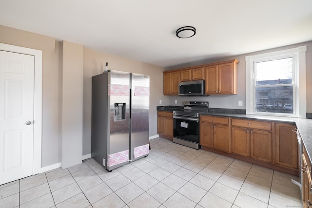 33 Prince St, Bristol, CT 06010 - kitchen with stainless steel appliances, healthy amount of natural light, brown cabinetry, and light tile patterned flooring