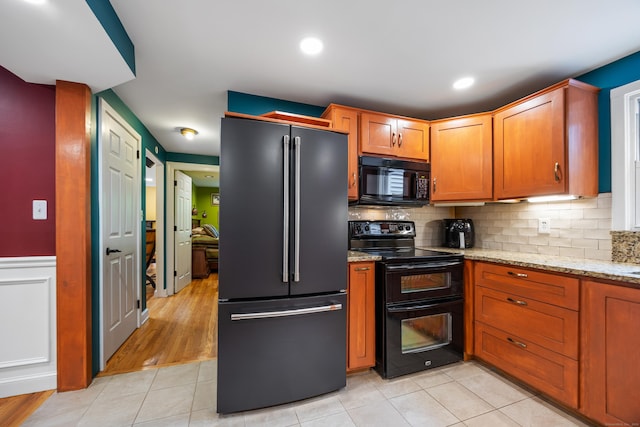 1 Russell Ln, Simsbury, CT 06070 - kitchen with black appliances, light tile patterned floors, light stone countertops, decorative backsplash, and a wainscoted wall