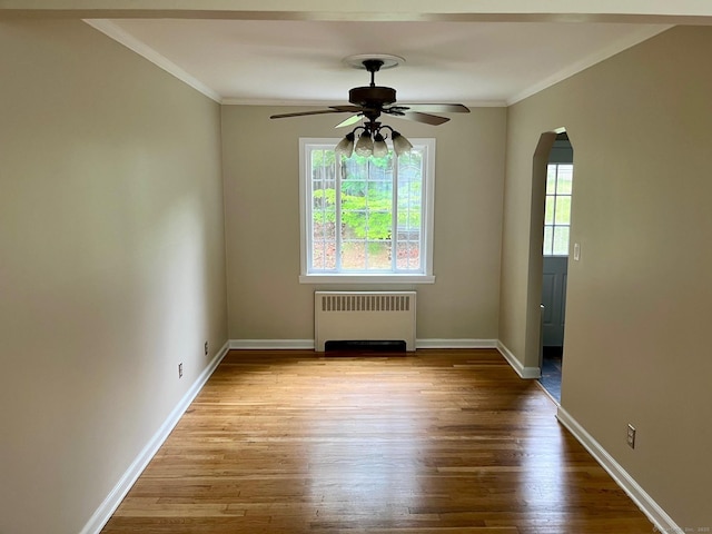219 French St, Bristol, CT 06010 - spare room with radiator heating unit, crown molding, arched walkways, a ceiling fan, and wood finished floors