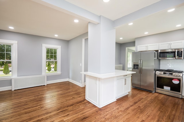314 Skiff St, North Haven, CT 06473 - kitchen with appliances with stainless steel finishes, radiator heating unit, wood finished floors, light countertops, and decorative backsplash