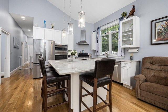 194 Killdeer Rd, Webster, MA 01570 - kitchen with wall chimney exhaust hood, stainless steel appliances, light stone counters, white cabinetry, and high vaulted ceiling
