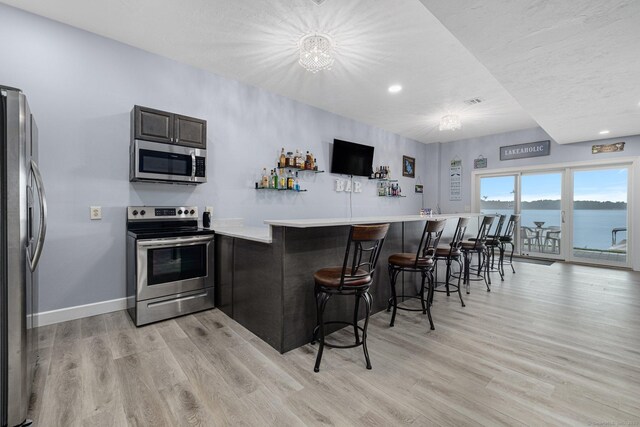 194 Killdeer Rd, Webster, MA 01570 - kitchen featuring appliances with stainless steel finishes, light wood-style flooring, a kitchen bar, light countertops, and recessed lighting