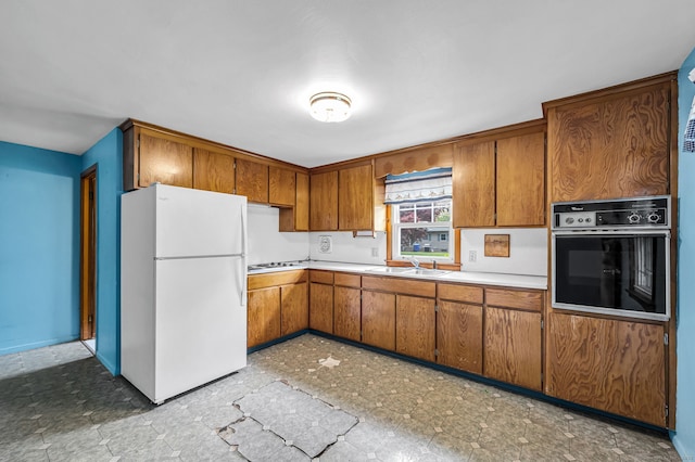 1 Pine Grove Ave, Enfield, CT 06082 - kitchen featuring oven, freestanding refrigerator, brown cabinetry, a sink, and light countertops
