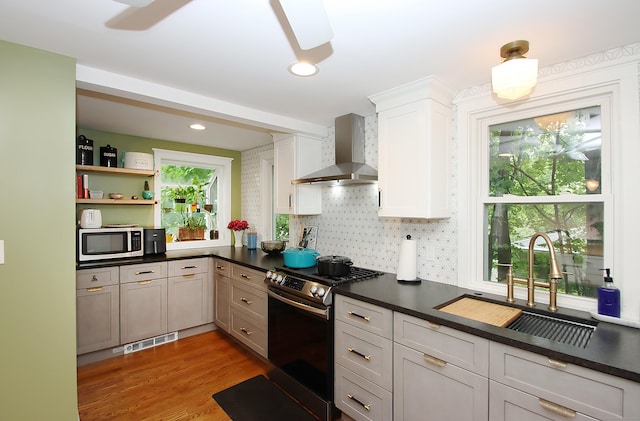 62 Mather St, Manchester, CT 06042 - kitchen featuring stainless steel appliances, wall chimney range hood, a sink, dark countertops, and plenty of natural light