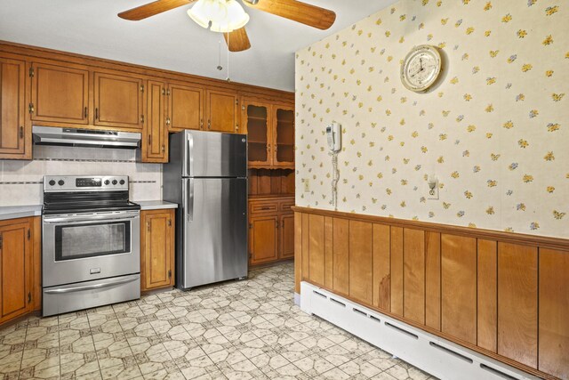 870 N Colony Rd, Meriden, CT 06450 - kitchen featuring appliances with stainless steel finishes, baseboard heating, under cabinet range hood, brown cabinetry, and wainscoting