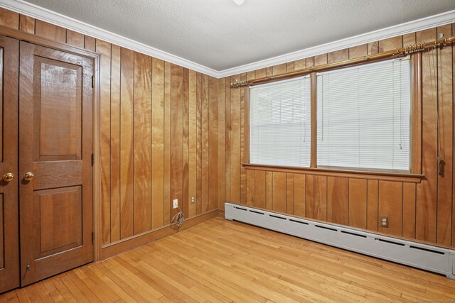 870 N Colony Rd, Meriden, CT 06450 - spare room with baseboard heating, hardwood / wood-style floors, wood walls, and crown molding