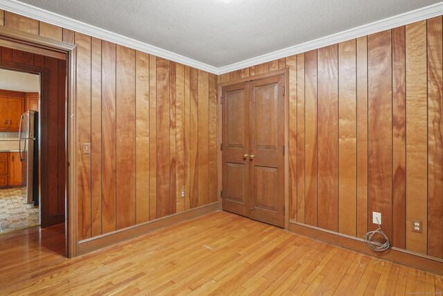 870 N Colony Rd, Meriden, CT 06450 - spare room featuring light wood-type flooring, wood walls, crown molding, and a textured ceiling
