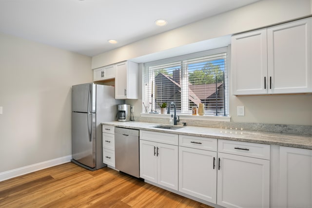 17 Hollow Tree Ln Unit 17, Monroe, CT 06468 - kitchen featuring appliances with stainless steel finishes, a sink, white cabinets, light wood-style floors, and light stone counters