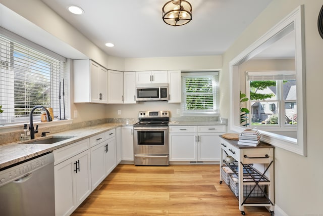 17 Hollow Tree Ln Unit 17, Monroe, CT 06468 - kitchen featuring appliances with stainless steel finishes, a sink, white cabinets, light wood-style flooring, and light stone countertops
