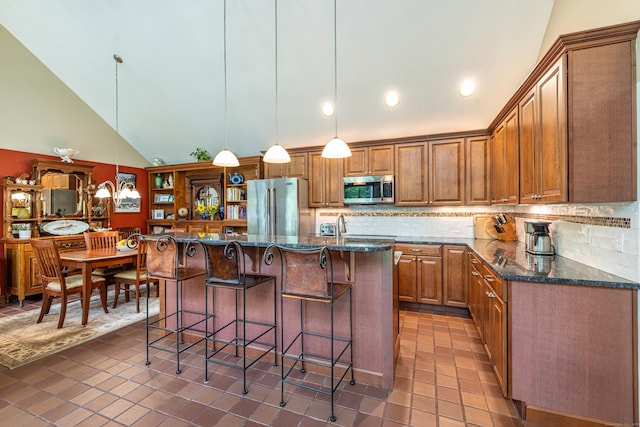 31 Philip Dr, Mansfield, CT 06268 - kitchen featuring stainless steel appliances, tasteful backsplash, brown cabinetry, dark stone countertops, and vaulted ceiling