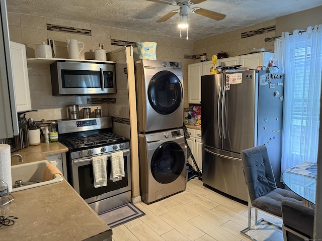 297 Laurel Ave, Bridgeport, CT 06605 - kitchen featuring stainless steel appliances, stacked washer / dryer, a sink, ceiling fan, and white cabinets