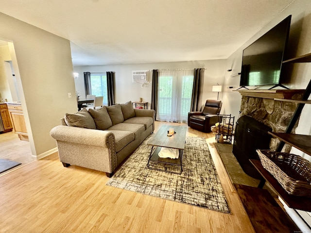 140 Hamden Ave Apt C, Waterbury, CT 06704 - living area featuring light wood-style flooring, an AC wall unit, a stone fireplace, and baseboards