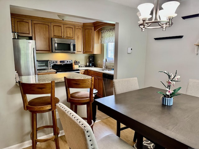 140 Hamden Ave Apt C, Waterbury, CT 06704 - kitchen with stainless steel appliances, a chandelier, a kitchen bar, a sink, and brown cabinets