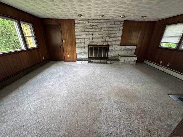 15 Zolan Dr, East Haven, CT 06513 - unfurnished living room featuring a stone fireplace, wooden walls, carpet floors, and a baseboard radiator