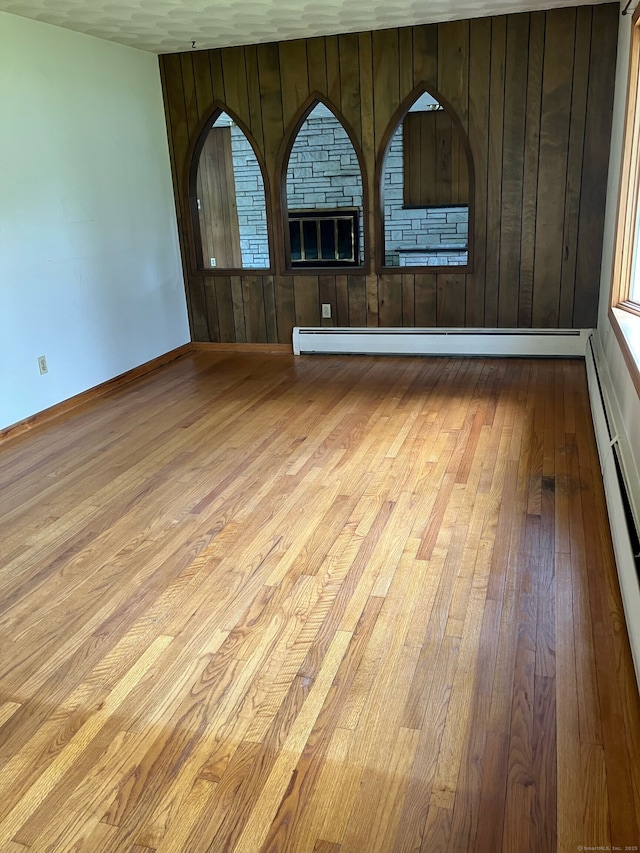 15 Zolan Dr, East Haven, CT 06513 - empty room with hardwood / wood-style flooring, baseboard heating, wood walls, and a baseboard radiator