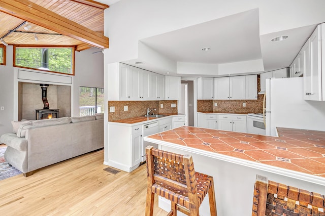 32 Old Bethel Rd, Newtown, CT 06470 - kitchen with a peninsula, white appliances, white cabinets, a sink, and decorative backsplash