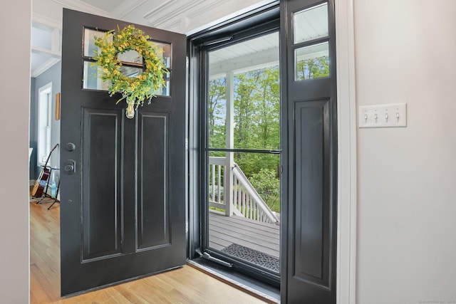 foyer with wood finished floors and ornamental molding