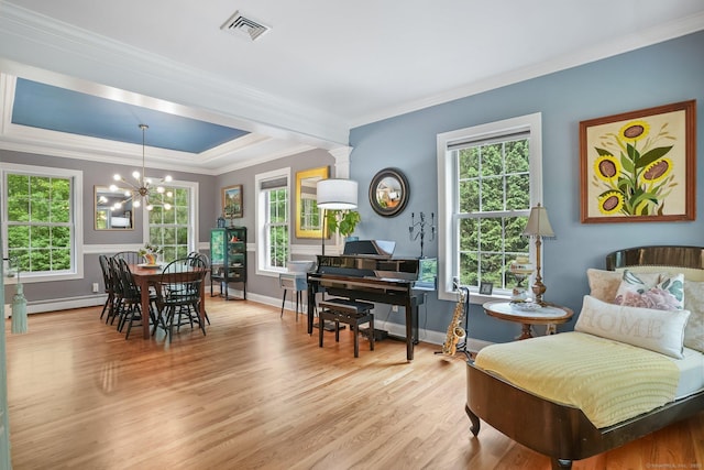 living area with baseboard heating, ornamental molding, healthy amount of natural light, light wood-style flooring, and a raised ceiling