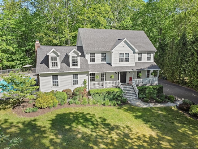 view of front of home with covered porch, a chimney, stairs, a front yard, and roof with shingles
