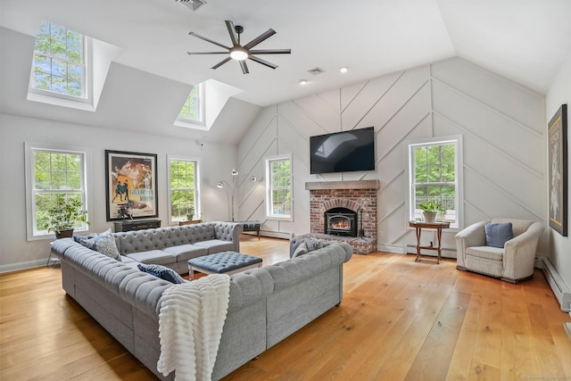 living area featuring a skylight, a baseboard heating unit, lofted ceiling, light wood finished floors, and plenty of natural light