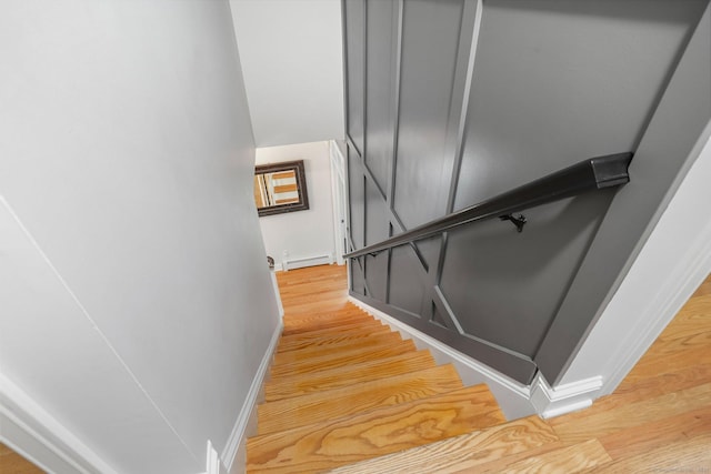 stairs with baseboard heating, baseboards, and wood finished floors