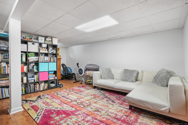 living area with wood finished floors, a drop ceiling, and baseboards