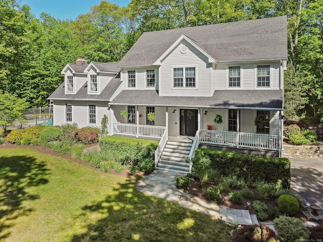 view of front of home with covered porch, roof with shingles, a chimney, a front lawn, and stairway