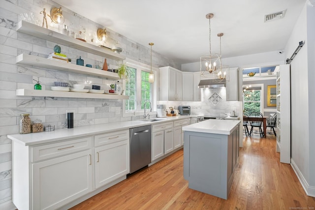 kitchen with dishwasher, decorative backsplash, a sink, light wood-style floors, and white cabinets