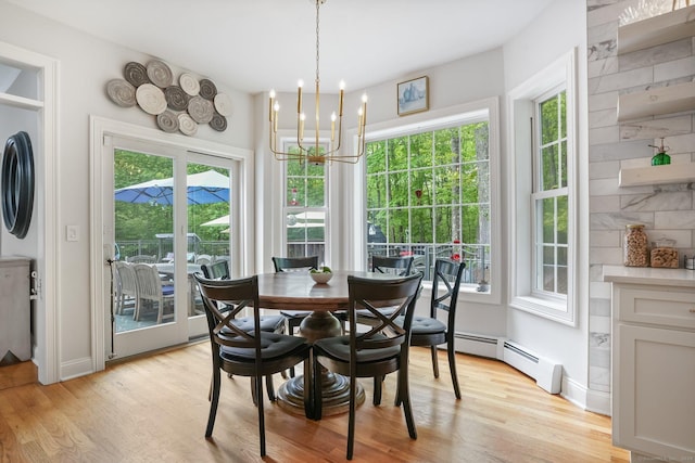 dining space with a baseboard radiator, light wood finished floors, a chandelier, and baseboards
