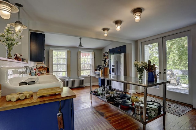 kitchen featuring radiator, blue cabinets, dark wood-type flooring, and french doors