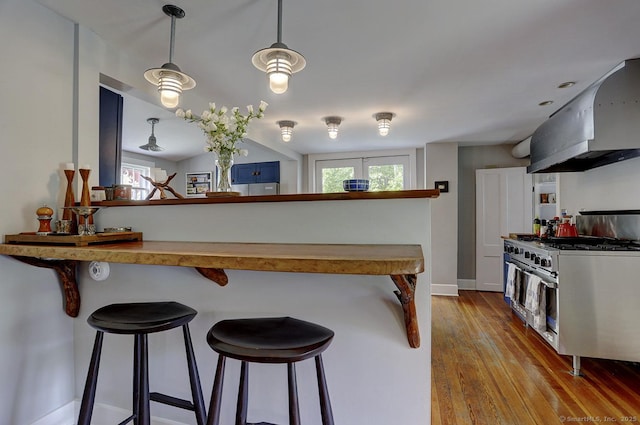 kitchen with double oven range, extractor fan, a breakfast bar area, and hardwood / wood-style floors