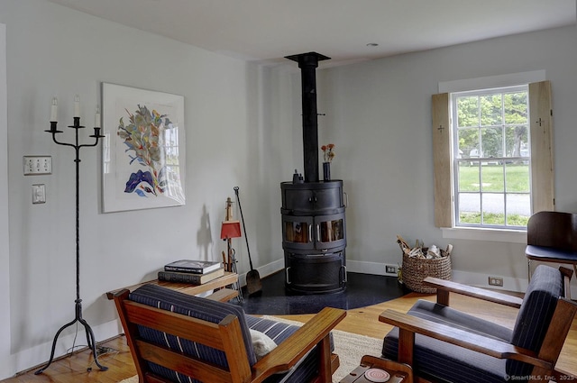 living room with wood finished floors, a wood stove, and baseboards