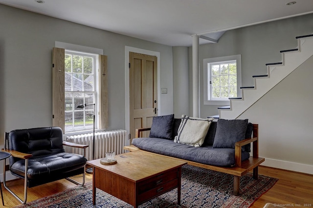 living room with radiator, wood finished floors, stairway, baseboards, and recessed lighting