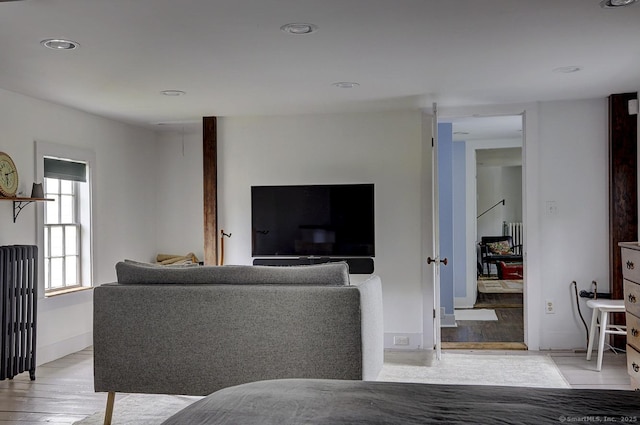 living area with radiator, light wood-type flooring, and recessed lighting