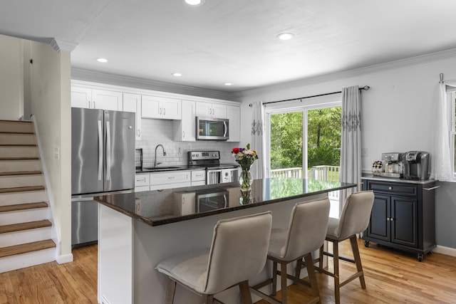 15 Ridgewood Dr, Monroe, CT 06468 - kitchen featuring stainless steel appliances, a sink, a breakfast bar, light wood-style flooring, and crown molding
