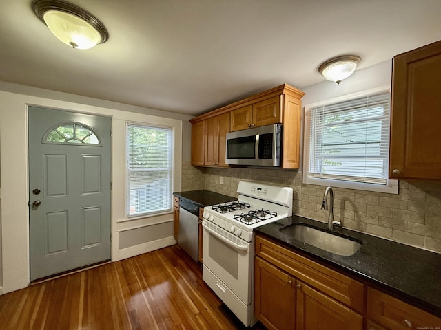 16-1/2 W Main St, Norwalk, CT 06851 - kitchen featuring appliances with stainless steel finishes, a sink, dark wood-style floors, decorative backsplash, and brown cabinets