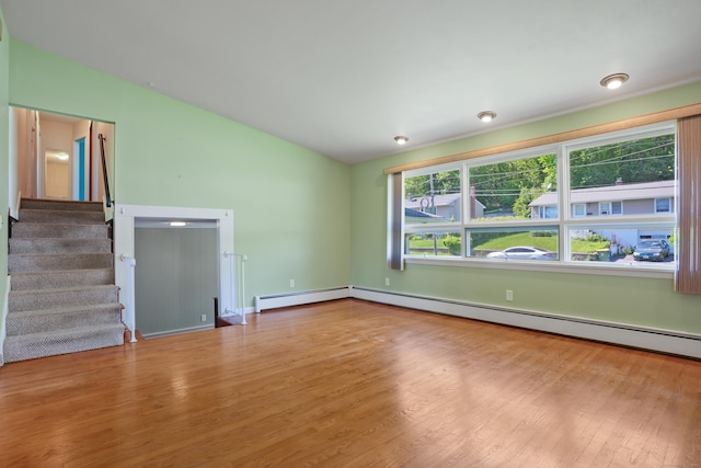 101 Rosengarten Dr, Waterbury, CT 06704 - unfurnished living room featuring wood finished floors, vaulted ceiling, a baseboard radiator, and stairway