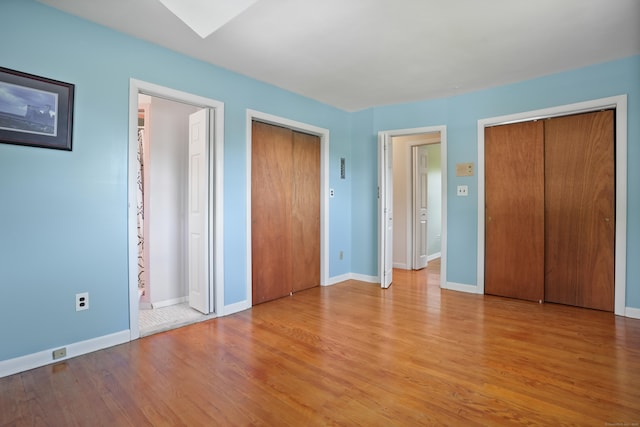 101 Rosengarten Dr, Waterbury, CT 06704 - unfurnished bedroom featuring multiple closets, light wood-type flooring, a skylight, and baseboards