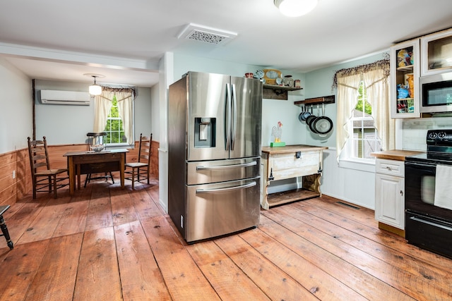 538 Scotland Rd, Norwich, CT 06360 - kitchen featuring stainless steel appliances, an AC wall unit, light wood-style floors, and glass insert cabinets
