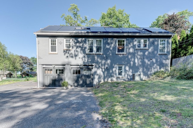 21 Elm St, Southington, CT 06479 - view of front of house with roof mounted solar panels, driveway, a garage, a front lawn, and stucco siding