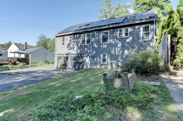 21 Elm St, Southington, CT 06479 - view of side of home with asphalt driveway, an attached garage, roof mounted solar panels, and a yard