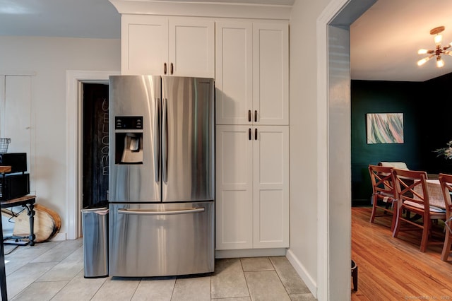 21 Elm St, Southington, CT 06479 - kitchen with stainless steel fridge, light tile patterned floors, white cabinets, and a chandelier