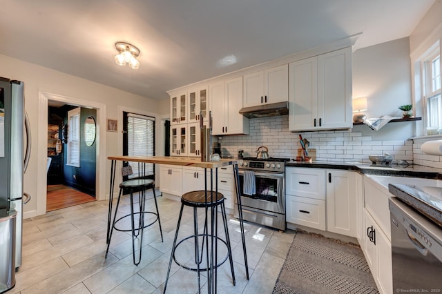 21 Elm St, Southington, CT 06479 - kitchen featuring stainless steel appliances, under cabinet range hood, tasteful backsplash, white cabinetry, and glass insert cabinets