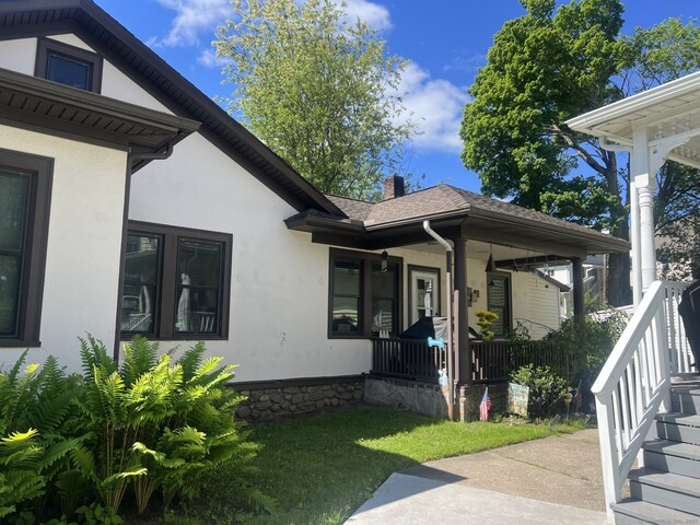 66 Seymour Ave, Derby, CT 06418 - view of property exterior with covered porch, stucco siding, a chimney, roof with shingles, and a lawn
