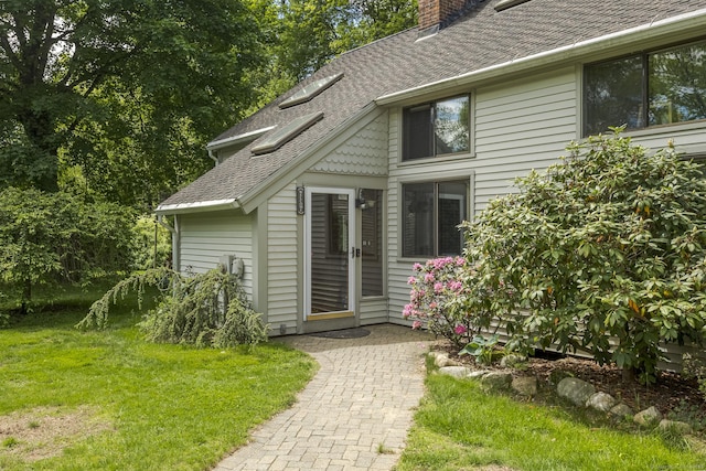 18 Grey Fox Trl, Woodbury, CT 06798 - view of exterior entry with a chimney, a shingled roof, and a yard