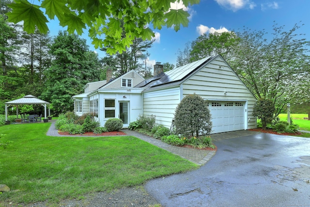 691 Buttonball Rd, Orange, CT 06477 - view of front of property with a chimney, a gazebo, roof mounted solar panels, a front yard, and driveway